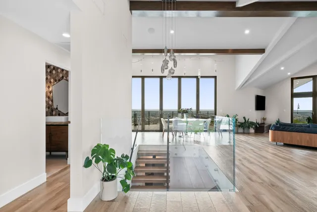 a living room with furniture potted plant floor to ceiling window and a flat screen tv