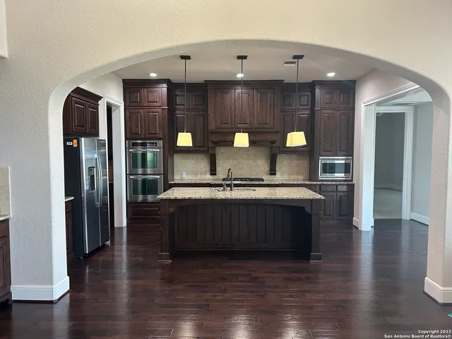 a kitchen with a wooden floor and a view of living room