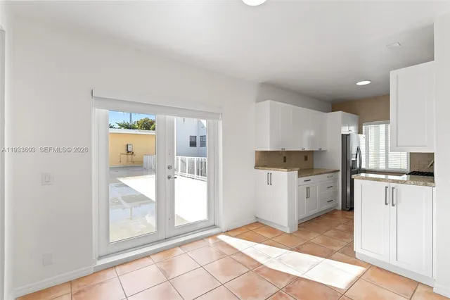 a kitchen with a stove a refrigerator and white cabinets with wooden floor