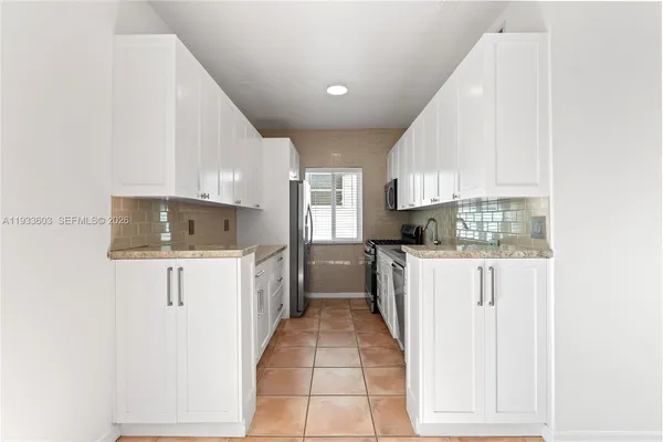 a kitchen with a refrigerator and white cabinets