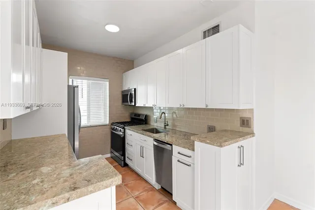 a kitchen with kitchen island granite countertop a sink stove and refrigerator