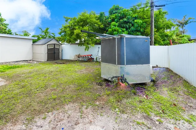 a backyard of a house with table and chairs plants and large tree