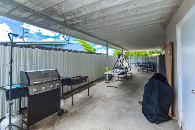 a view of a patio with table and chairs under an umbrella with a small yard