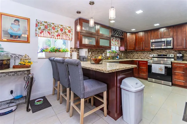 a kitchen with stainless steel appliances granite countertop a sink a stove a refrigerator cabinets and living room view