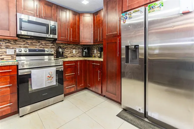 a kitchen with stainless steel appliances granite countertop a stove a sink and a microwave