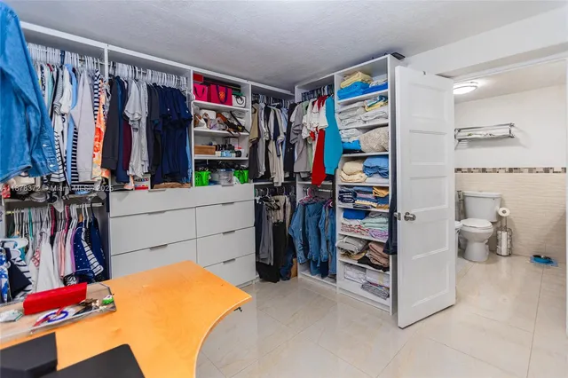 a view of walk in closet with clothes and shoes