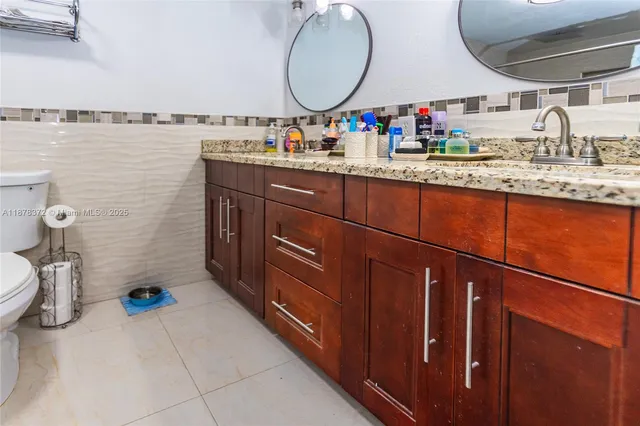 a bathroom with a granite countertop sink a mirror and a toilet