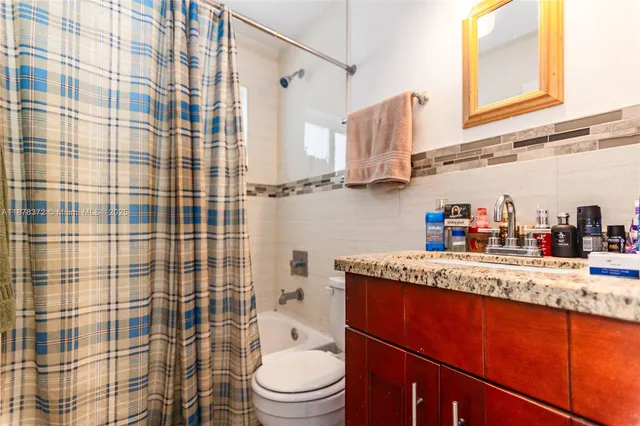 a bathroom with a granite countertop sink a toilet and shower