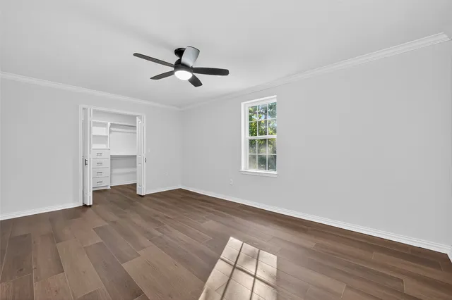 a view of empty room with wooden floor and ceiling fan