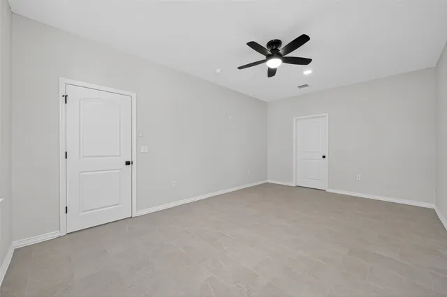 an empty room with windows and fan