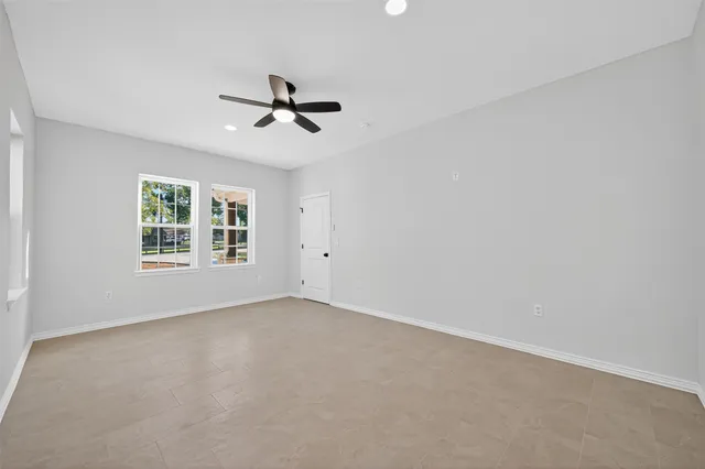an empty room with windows and fan