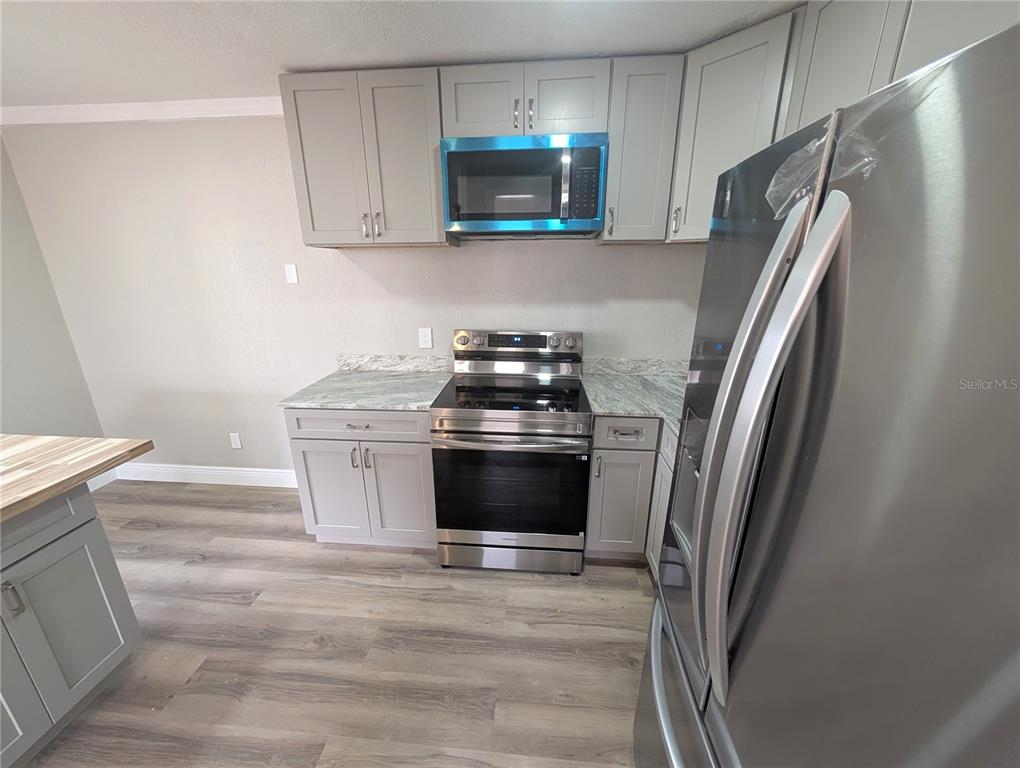 5521 Bay Boulevard, Unit 201 Port Richey, FL 34668 - Photo 3 of 12 a kitchen with stainless steel appliances wooden floor sink and stove