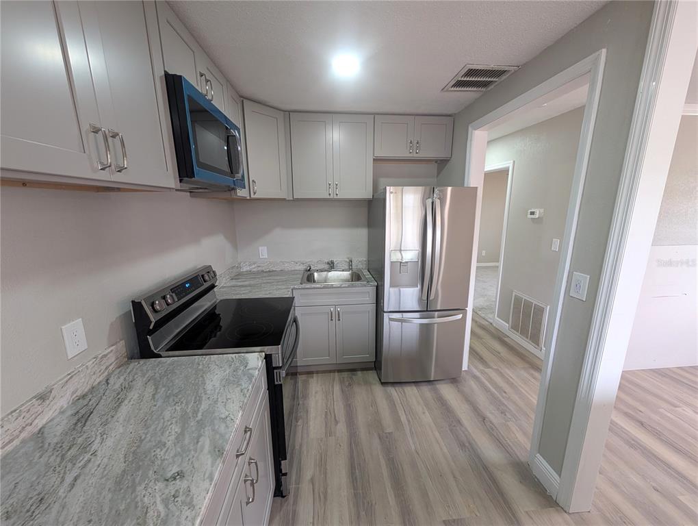 5521 Bay Boulevard, Unit 201 Port Richey, FL 34668 - Photo 4 of 12 a kitchen with a refrigerator sink and cabinets
