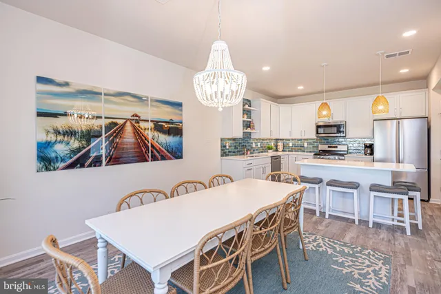 a view of a dining room with furniture a kitchen and chandelier