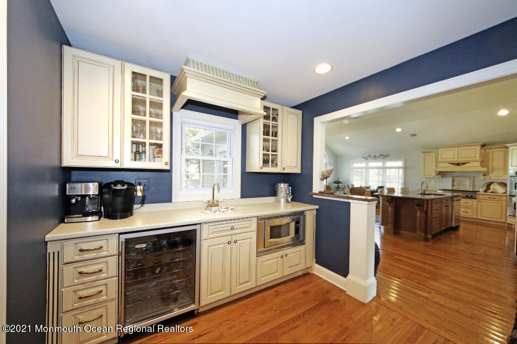 1132 Mohegan Road Manasquan, NJ 08736 - Photo 24 of 35 a kitchen with a stove a sink and white cabinets with wooden floor