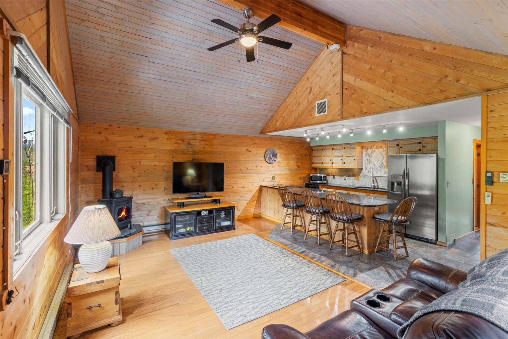 1516 Blue Ridge Road Silverthorne, CO 80498 - Photo 2 of 50 Living room featuring healthy amount of natural light, wood walls, a wood stove, ceiling fan, and high vaulted ceiling
