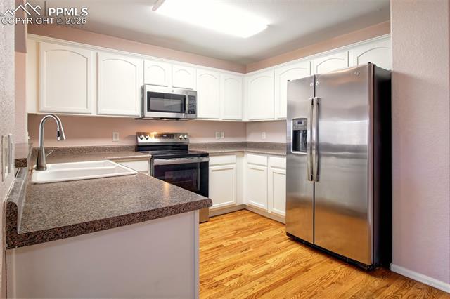 3579 Indigo Ridge Point Colorado Springs, CO 80910 - Photo 6 of 33 Kitchen with wood floors, stainless steel appliances and ample cabinet space