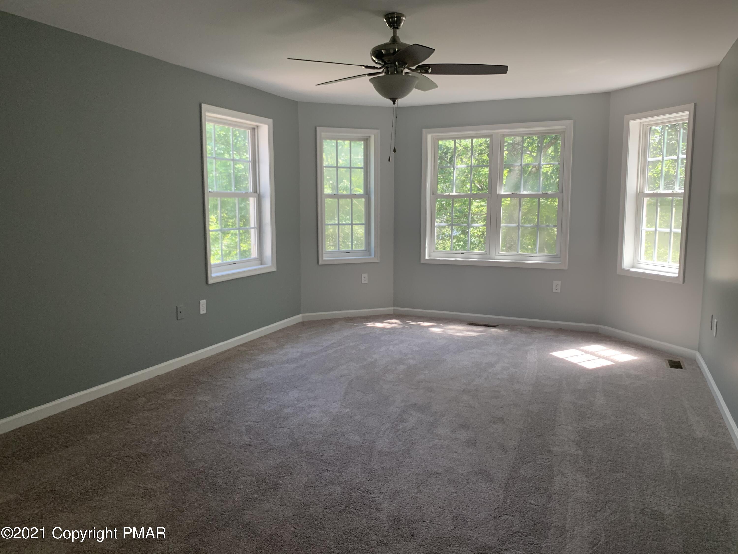136 Pike Road Bushkill, PA 18324 - Photo 7 of 35 en empty room with windows and chandelier fan