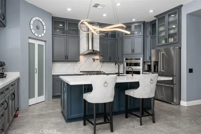 a kitchen with stainless steel appliances kitchen island granite countertop a table chairs and a refrigerator