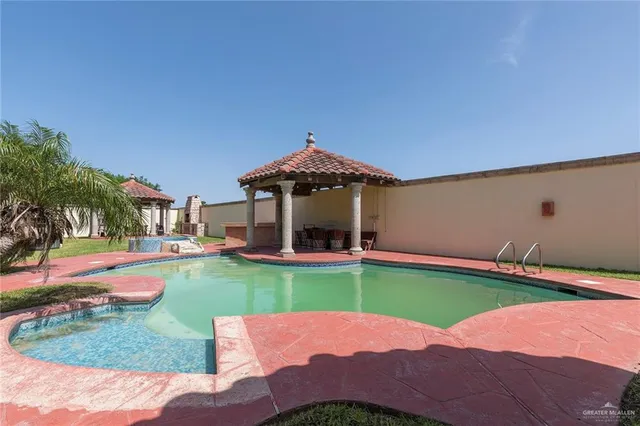 a view of a swimming pool with lawn chairs under an umbrella