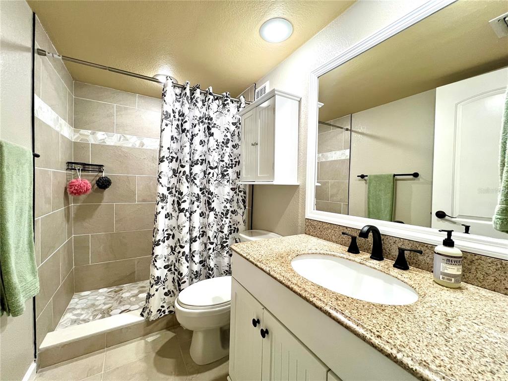 2101 Hammock Pine Boulevard, Unit 2101 Clearwater, FL 33761 - Photo 16 of 24 a bathroom with a granite countertop sink toilet and shower