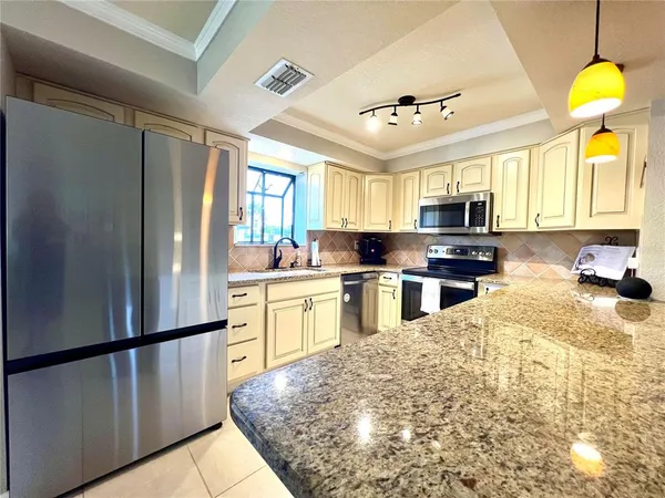 a kitchen with kitchen island granite countertop a sink stainless steel appliances cabinets and a window