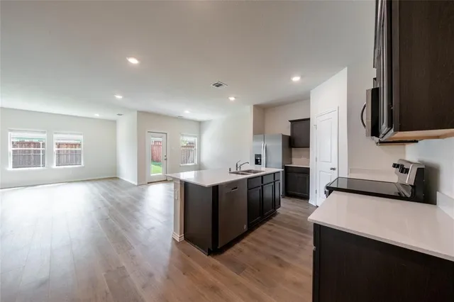 a large kitchen with stainless steel appliances granite countertop a large counter top a stove and a wooden floors