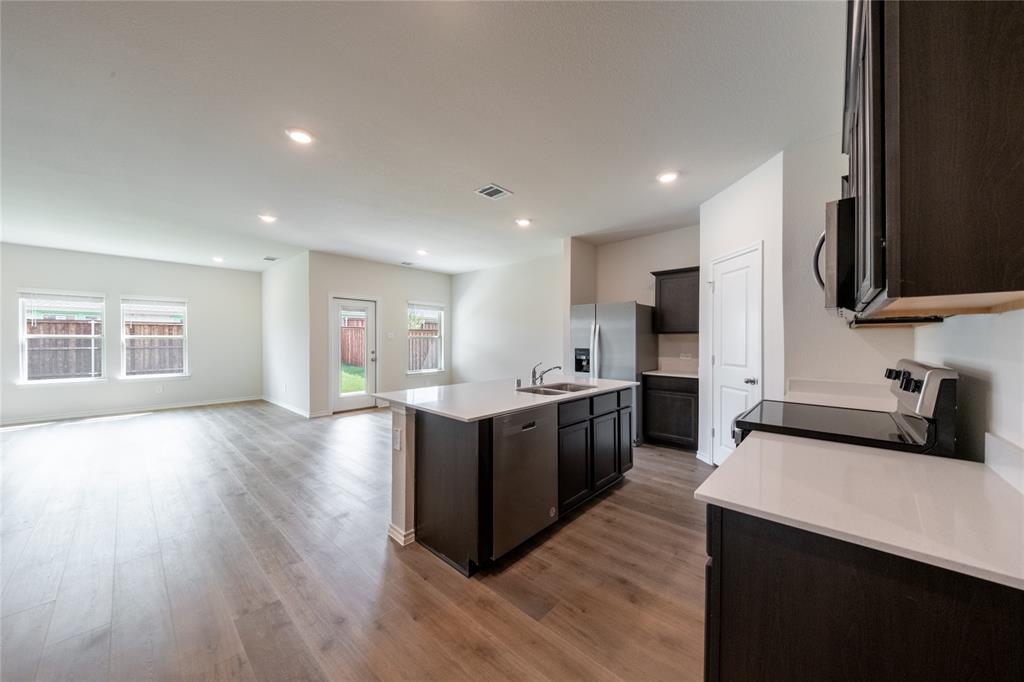 13156 Dawson Drive Providence Village, TX 76227 - Photo 7 of 31 a large kitchen with stainless steel appliances granite countertop a large counter top a stove and a wooden floors