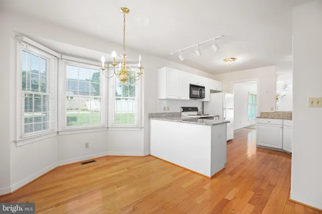 a kitchen with stainless steel appliances granite countertop a stove top oven a sink dishwasher and a refrigerator with wooden floor