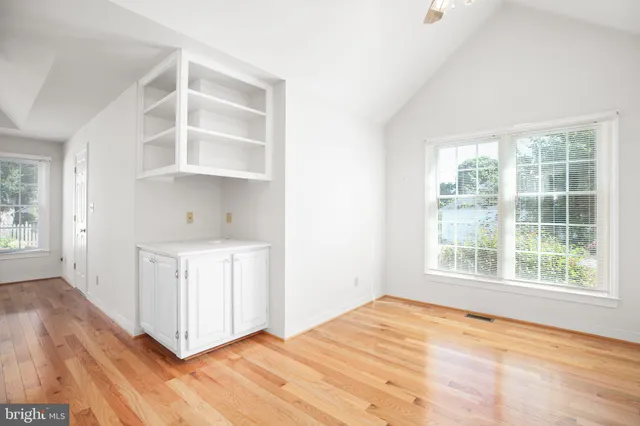 a view of an empty room with a window and wooden floor