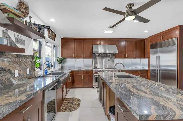 a kitchen with kitchen island granite countertop a sink cabinets and stainless steel appliances