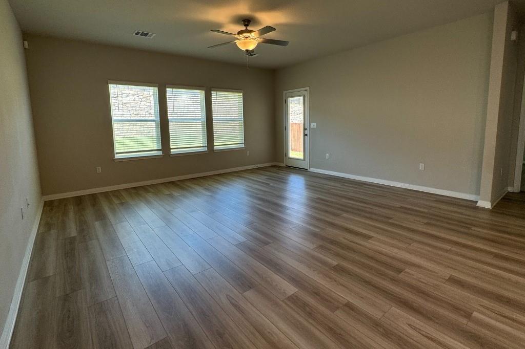 12604 Dairywork Road Buda, TX 78610 - Photo 6 of 20 A well-lit living area features durable laminate flooring and direct backyard access.