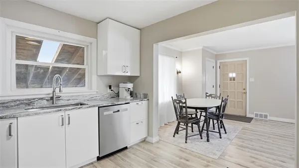 a kitchen with a sink dishwasher a dining table and chairs with wooden floor