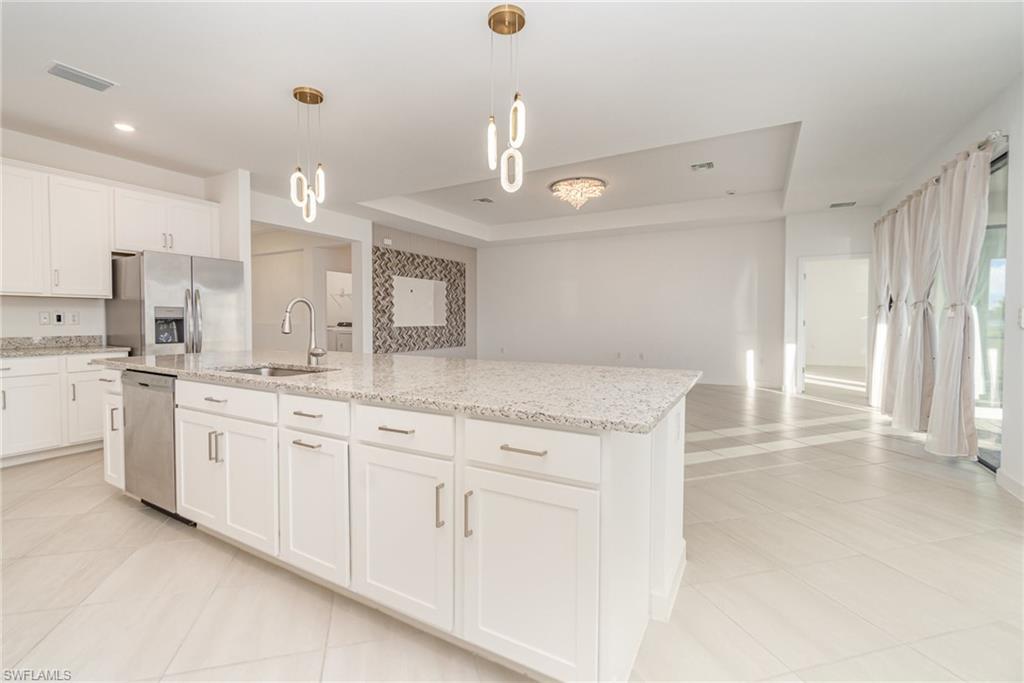 11127 Canopy Loop Fort Myers, FL 33913 - Photo 3 of 29 Kitchen with a raised ceiling, white cabinetry, stainless steel appliances, light stone countertops, and pendant lighting