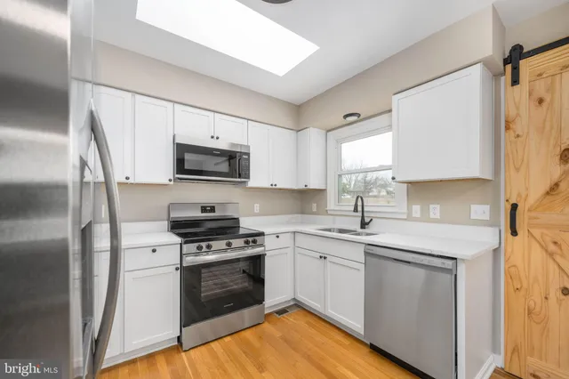 a kitchen with a sink cabinets stainless steel appliances and a window