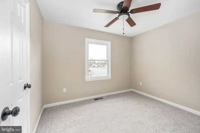 an empty room with a window and a fan