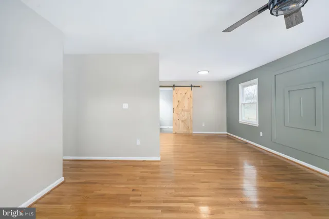 a view of an empty room with window and wooden floor