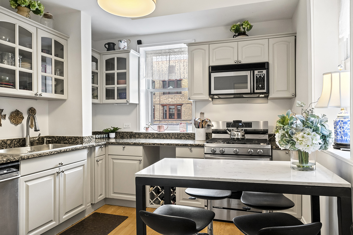 670 West Irving Park Road, Unit G6 Chicago, IL 60613 - Photo 22 of 38 a kitchen with stainless steel appliances white cabinets and a stove top oven