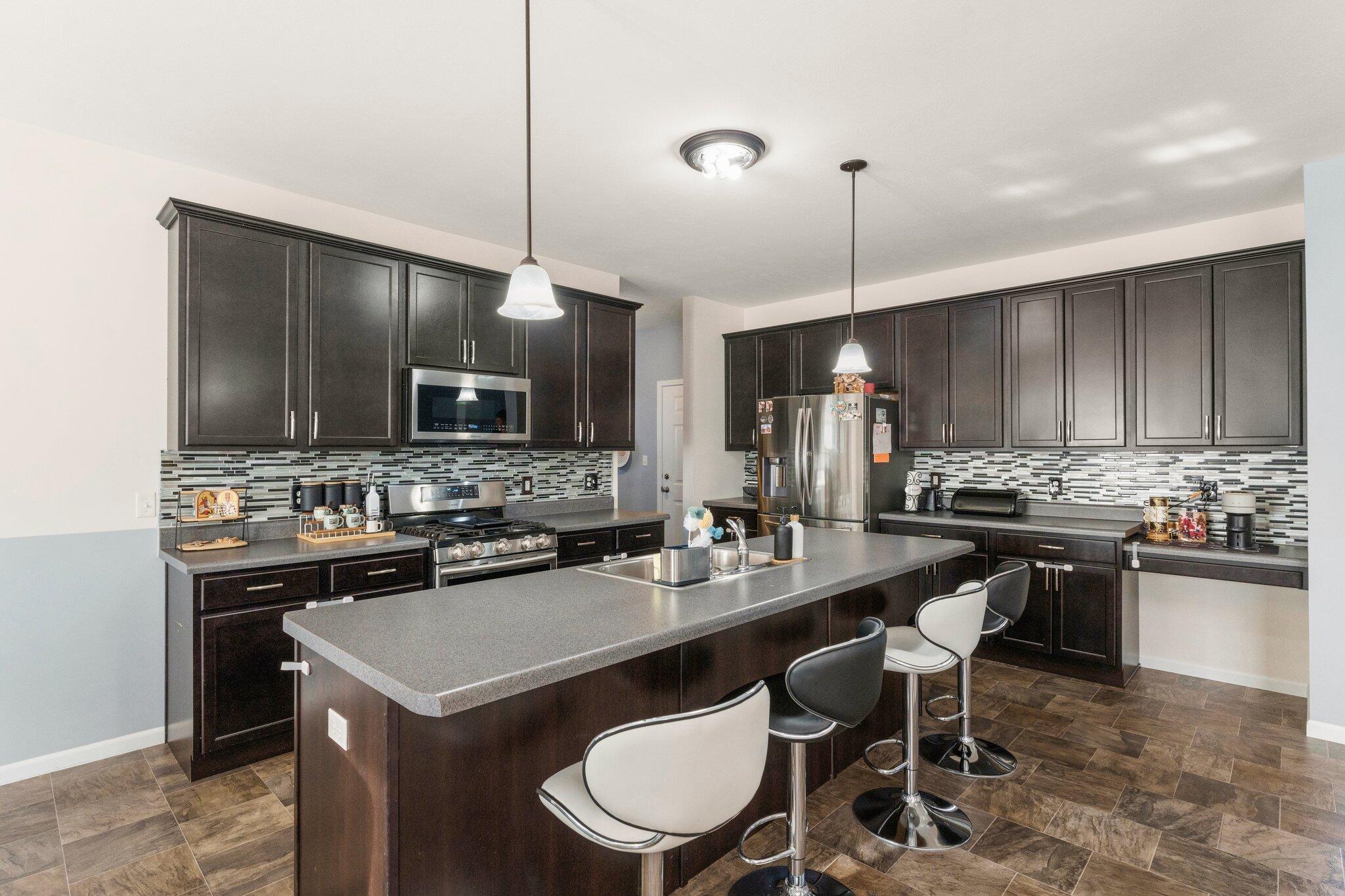 11539 Georgia Place Crown Point, IN 46307 - Photo 13 of 37 a kitchen with a sink a stove a kitchen island with chairs and cabinets
