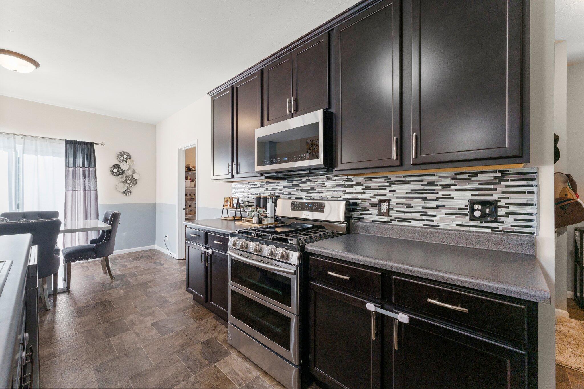 11539 Georgia Place Crown Point, IN 46307 - Photo 15 of 37 a kitchen with stainless steel appliances granite countertop a stove a sink and a microwave