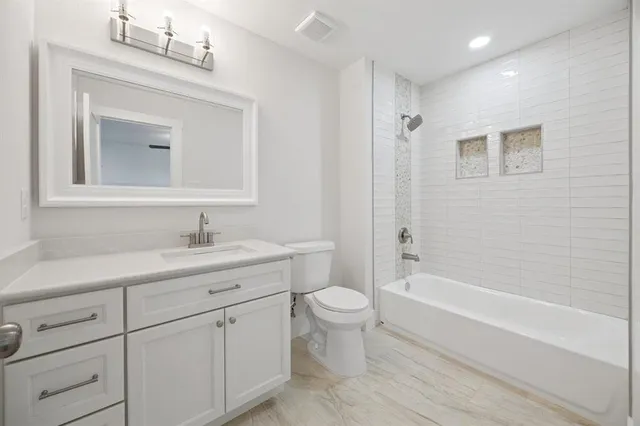 a bathroom with a toilet a sink a mirror a bathtub and vanity