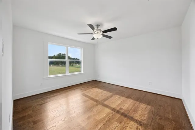 an empty room with windows and ceiling fan