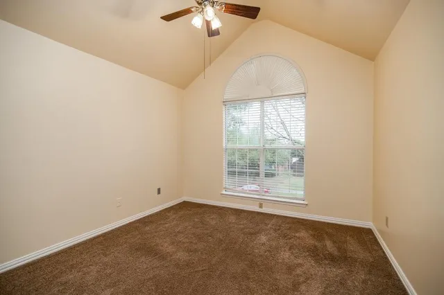 an empty room with a chandelier fan and windows