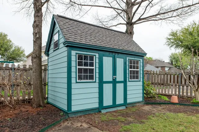 a view of a house that has a small yard and large trees