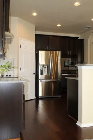 a view of a kitchen with a sink refrigerator and wooden floor