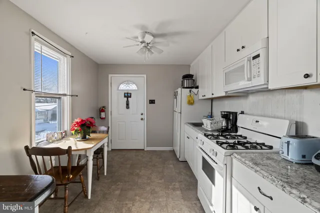 a kitchen with stainless steel appliances granite countertop a stove top oven a sink dishwasher and white cabinets with wooden floor