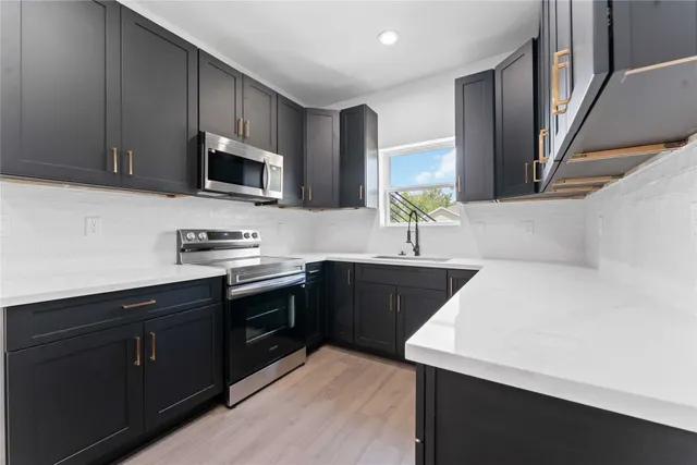 a kitchen with stainless steel appliances a sink dishwasher a stove top oven a refrigerator with wooden cabinets and cabinets