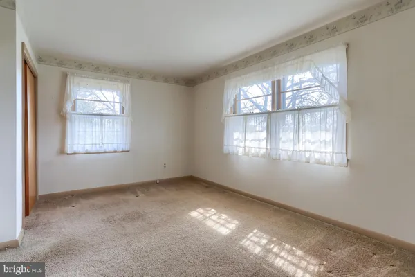 a view of an empty room with window and closet area