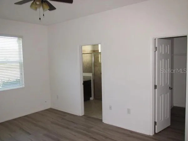 an empty room with wooden floor and chandelier fan