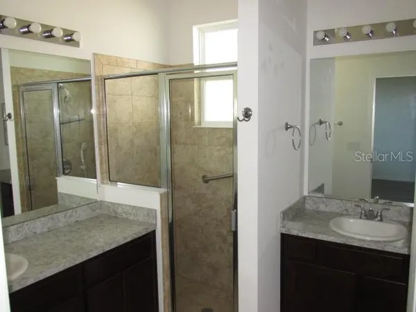 a bathroom with a granite countertop sink a mirror and shower